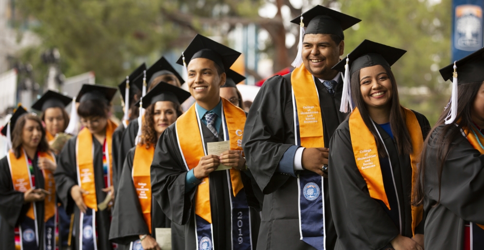 A diverse students smiling  at Cal State Fullerton graduation ceremony