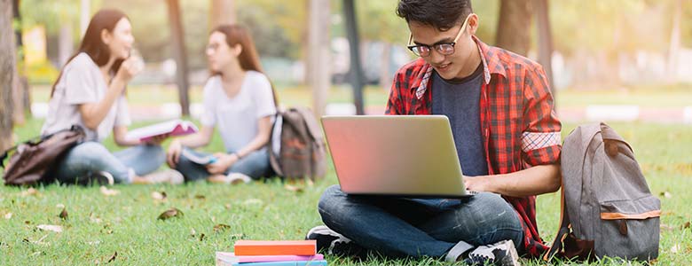Students working outdoors, sitting in the grass