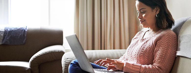 Woman sitting on couch using laptop