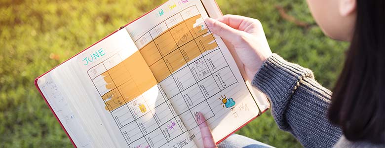 Woman holding a small planner with notes and highlighted dates