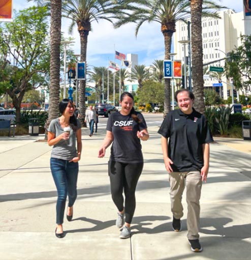 Three University Extension team members walking up the front pathway toward the College Park building