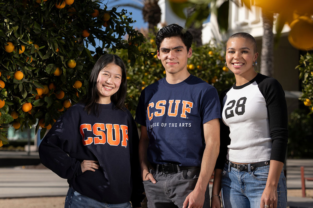 Three students posing on campus while wearing Titan shirts.