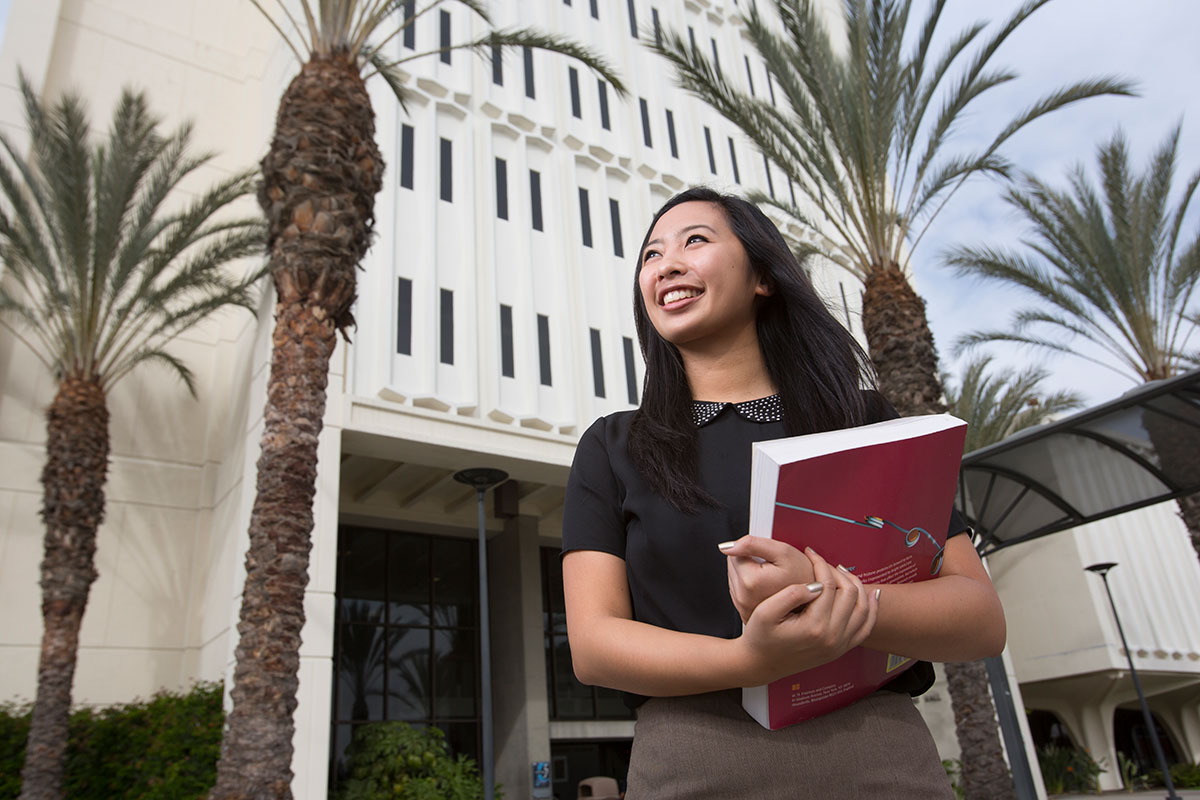 An asian lady walking on campus with a smile.