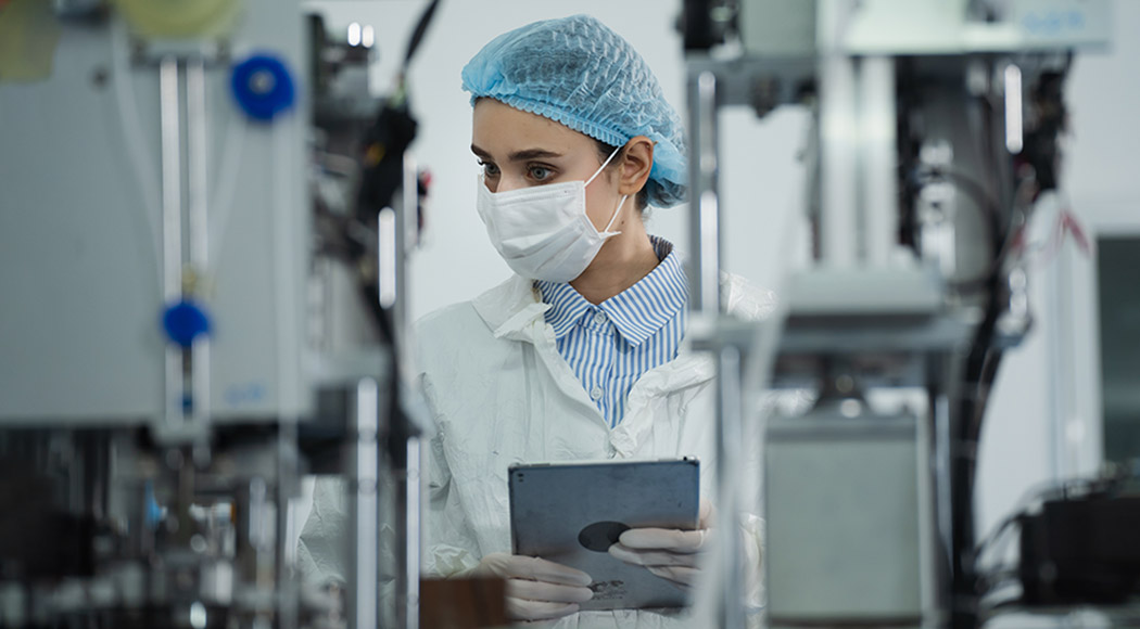 A female biomanufacturing techinian checking on beakers