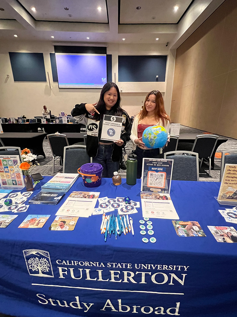 Two females holding Study Abroad Fair Event Goods